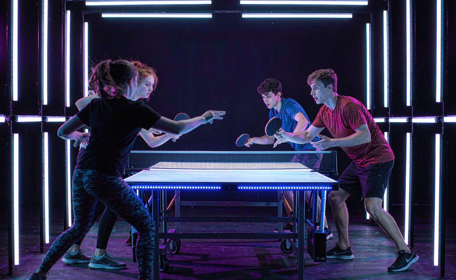 Doubles match in a neon-lit room